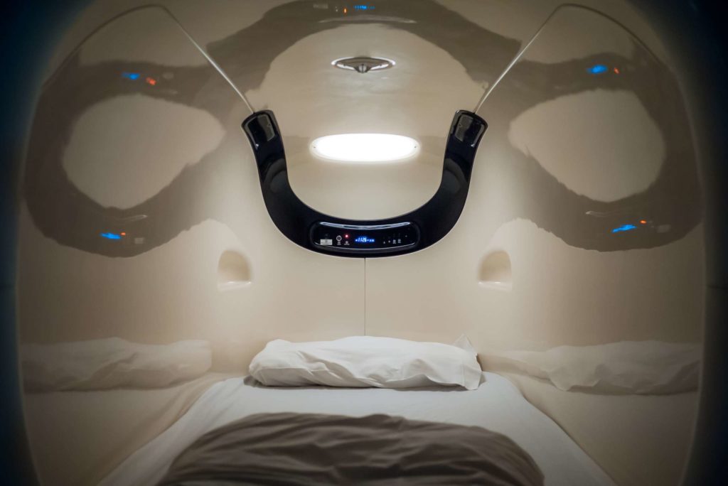 Futuristic sleeping capsule with ambient lighting at the Nine Hours capsule hotel in Kyoto, Japan